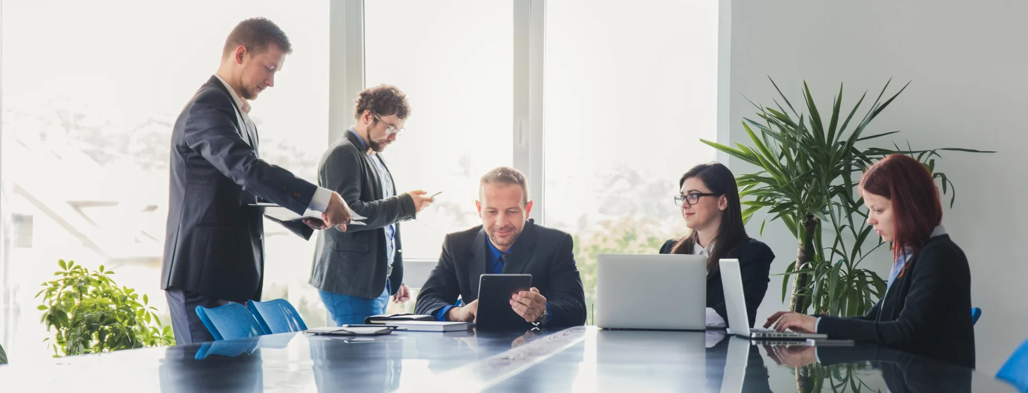 Team meeting in an office discussing work on laptops